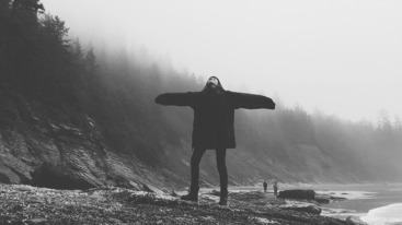 Twelve Year Old Girl On Beach With Arms Stretched  Towards Overcast Sky