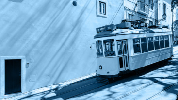 Yellow tram moving past yellow building in Lisbon, Portugal