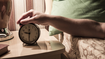 Caucasian man turning off alarm clock