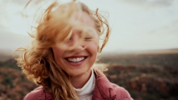 Vrouw heeft ogen gesloten en lacht gelukkig