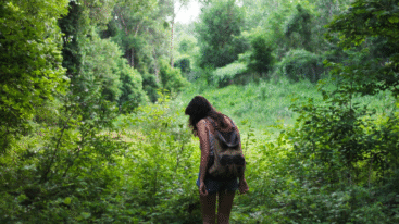 vrouw staat in de natuur vol met groene bomen