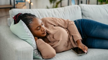 vrouw twijfelt over iemands uitnodiging afslaan omdat ze moe is en op de bank wil liggen