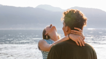 Een man en een vrouw die in elkaars armen vallen bij een meer en duidelijk verliefd zijn.