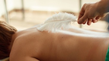 Een dame die met een veer wordt gekriebeld op haar rug.