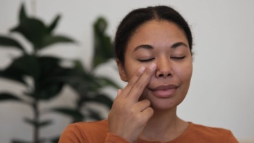 vrouw voert EFT tapping uit om een van de tapping points in het gezicht