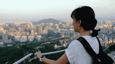 Jonge vrouw die kijkt naar een mooi uitzicht in een stad die lijkt op Rio de Janeiro.