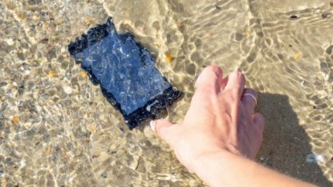 Telefoon die in de zee ligt en hand die hem probeert te pakken.