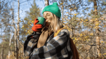 Een gelukkige vrouw die van haar thee geniet in de natuur