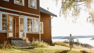 Mooi Zweeds huis bij een meer waar twee mensen genieten van het lekkeren weer