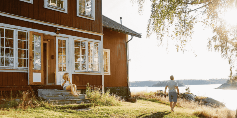 Mooi Zweeds huis bij een meer waar twee mensen genieten van het lekkeren weer