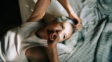 rust-out, vrouw ligt op bed met een streepje zon op haar gezicht