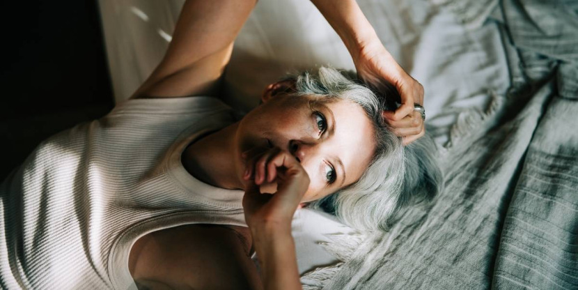 rust-out, vrouw ligt op bed met een streepje zon op haar gezicht